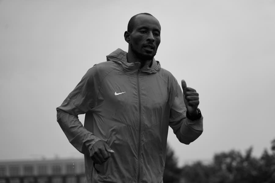 A runner in a rain jacket mid-stride on an overcast day