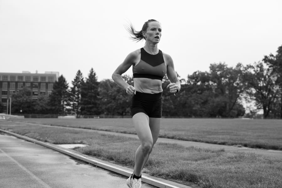 A woman running on an outdoor track during a workout