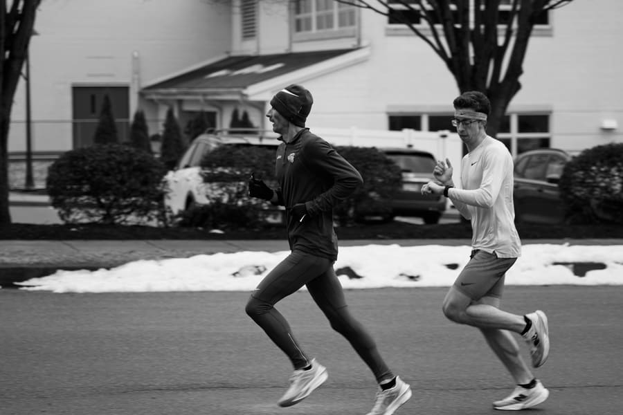Two runners on a snow-lined street during a winter training run