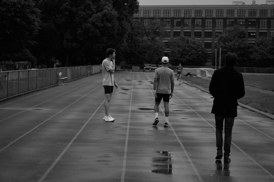 Three people on a wet outdoor track during a training session
